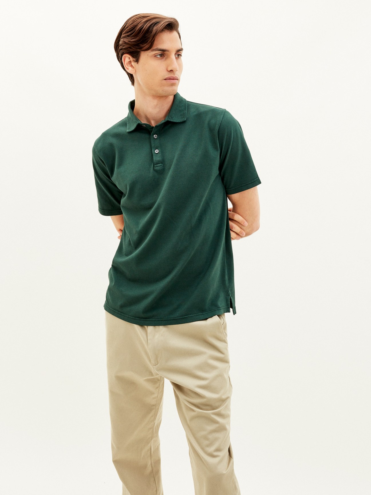 Man wearing forest green polo shirt with beige chinos against neutral background