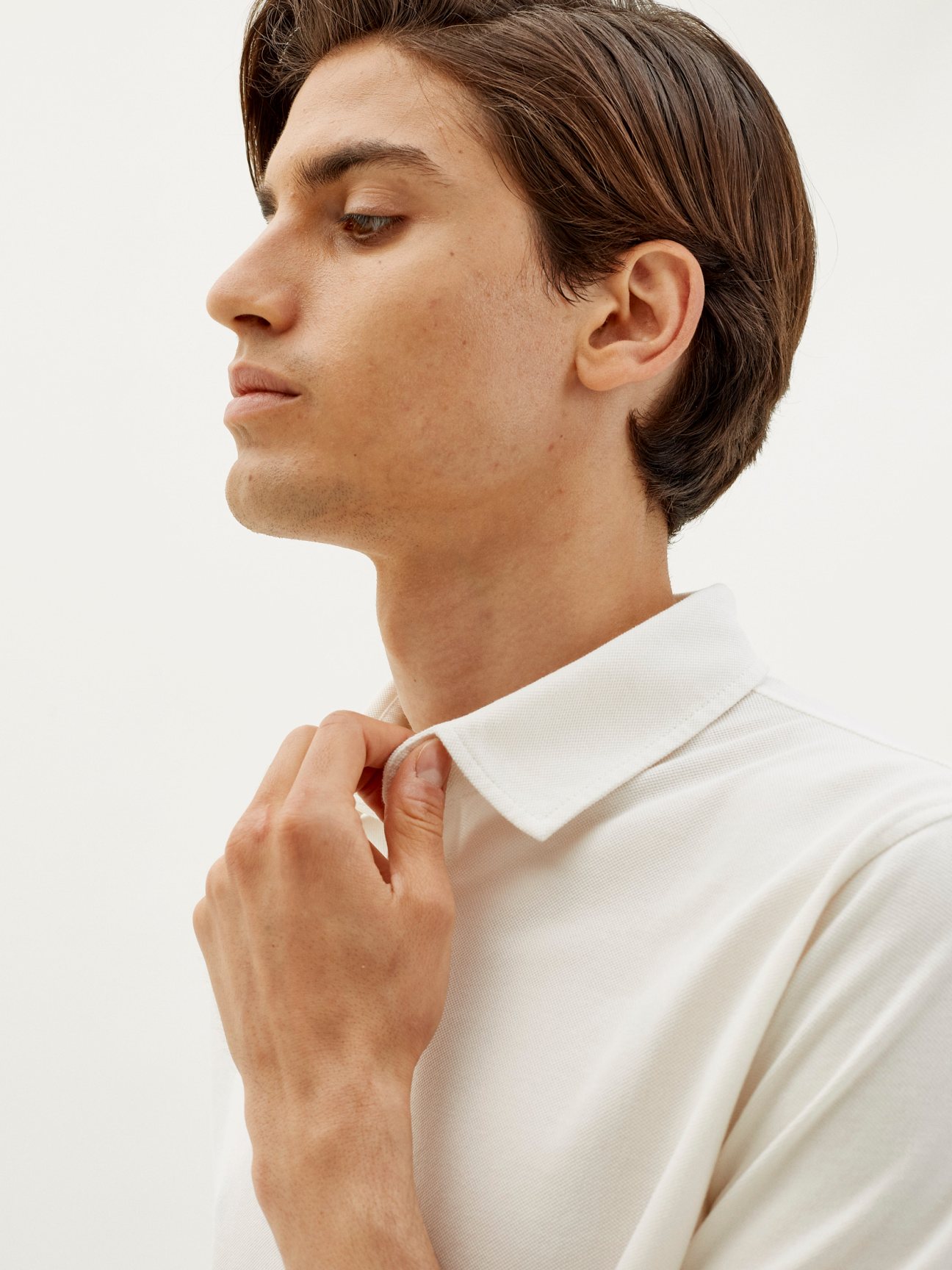 Man in profile wearing a warm white pique polo shirt by Trunk x Monocle