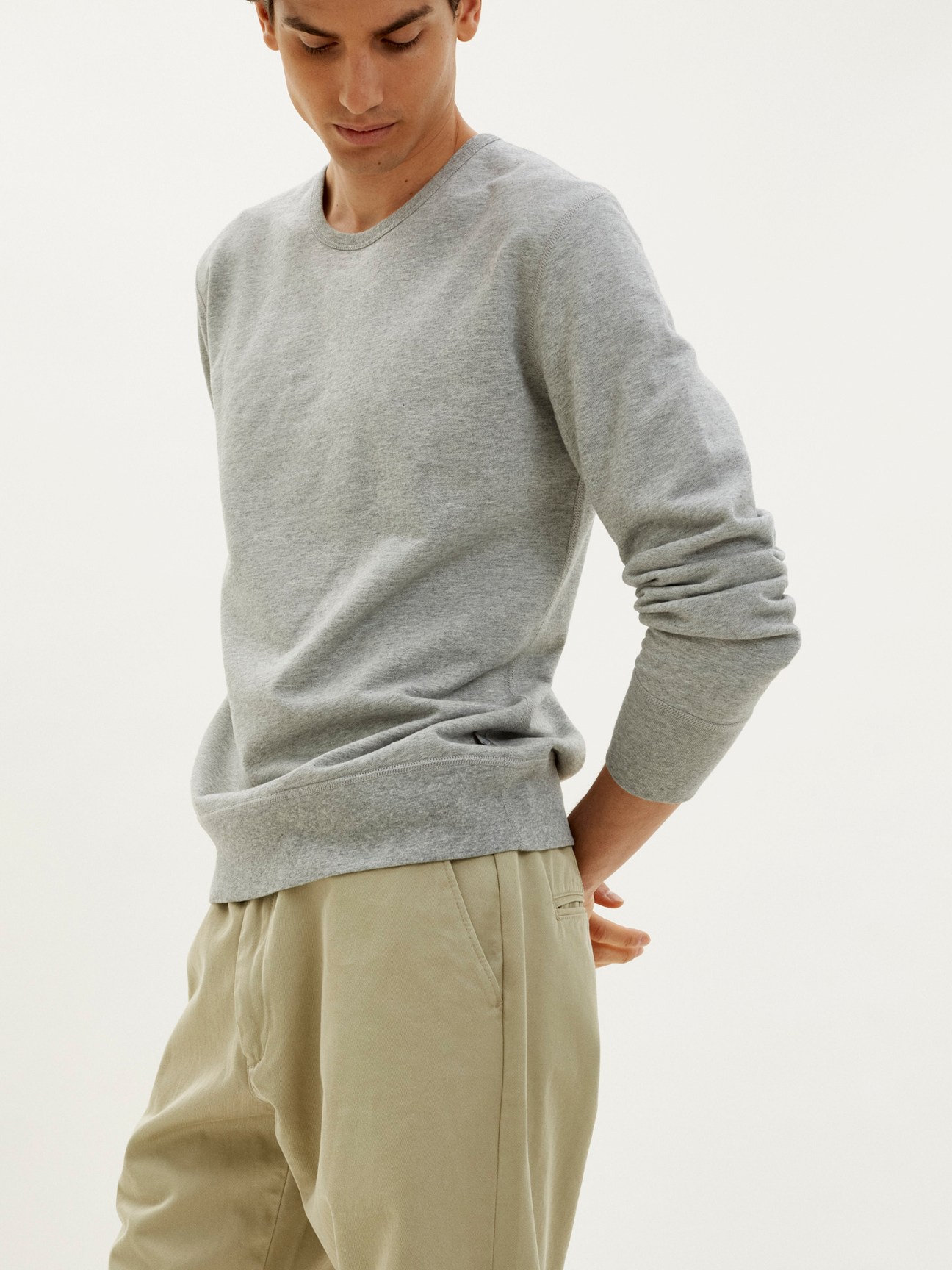Man wearing grey melange roundneck sweatshirt by Trunk x Monocle with beige trousers