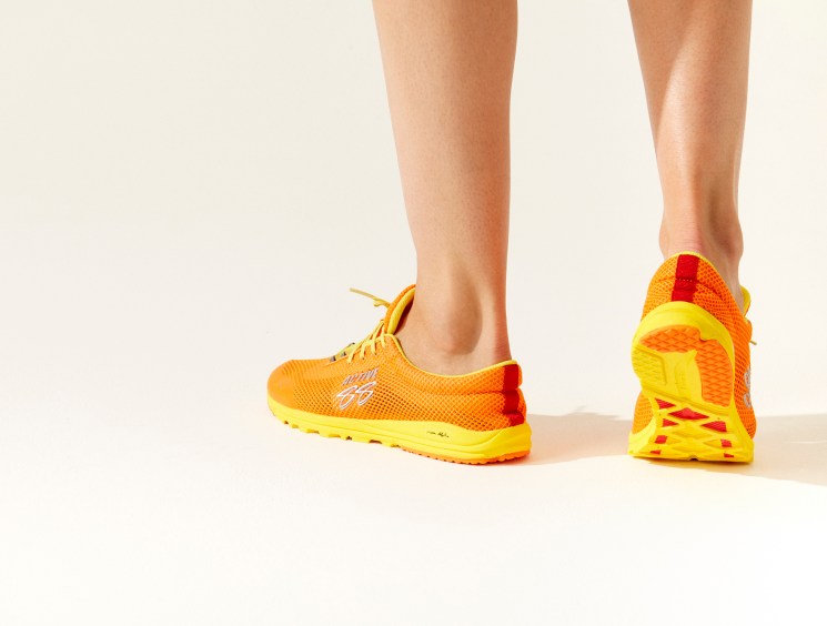Person wearing Boulder trainer by Active 88 in orange and yellow colorway on legs against neutral background