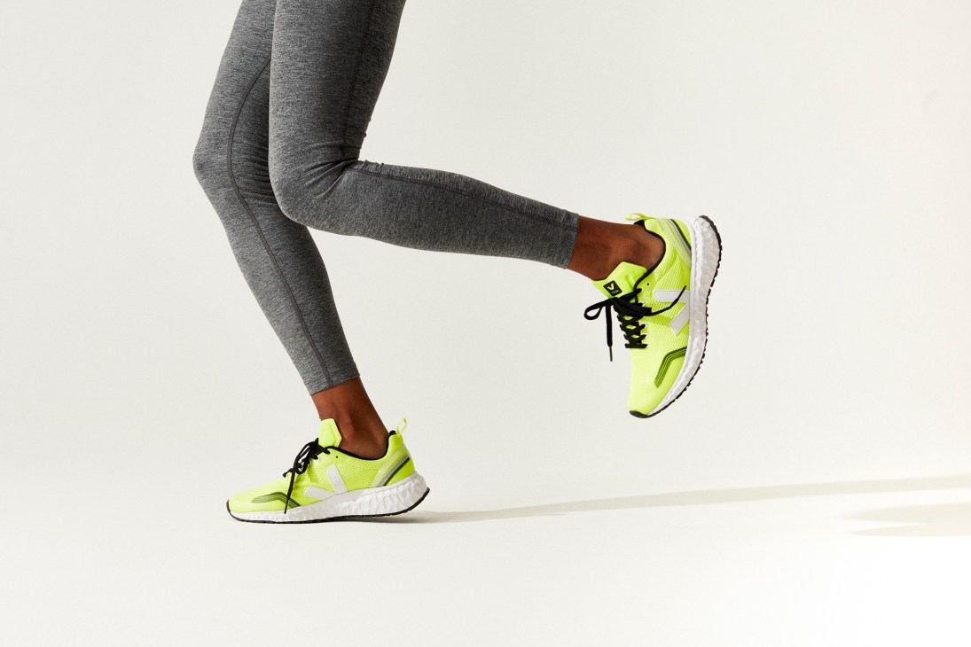 Person in grey leggings and bright green running shoes in dynamic running pose