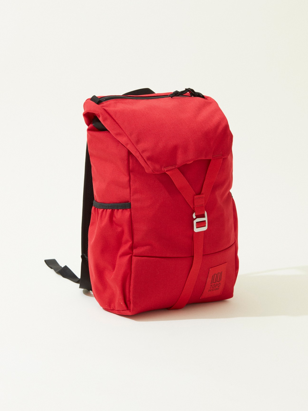 Red canvas backpack with black straps and buckle closure on white background