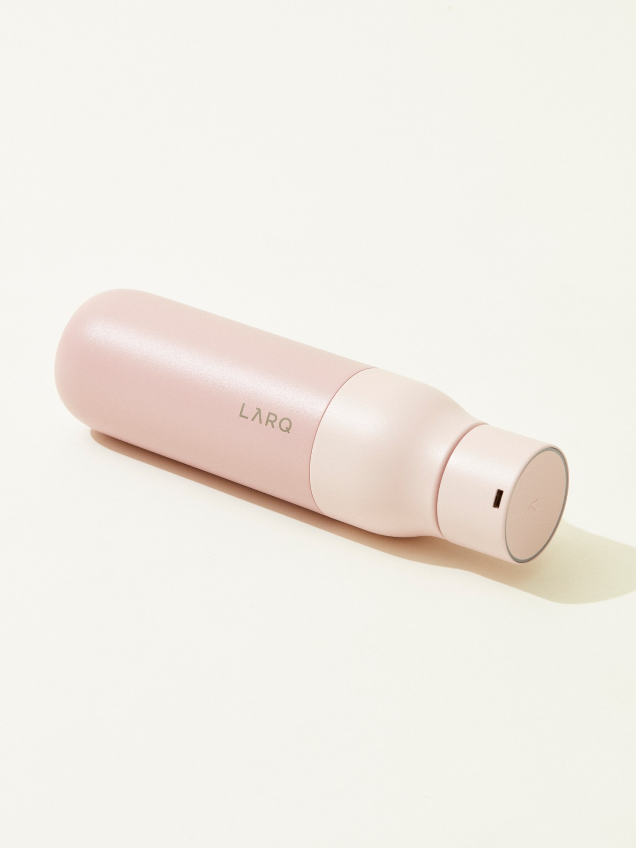 Pink cylindrical Larq water bottle on white background