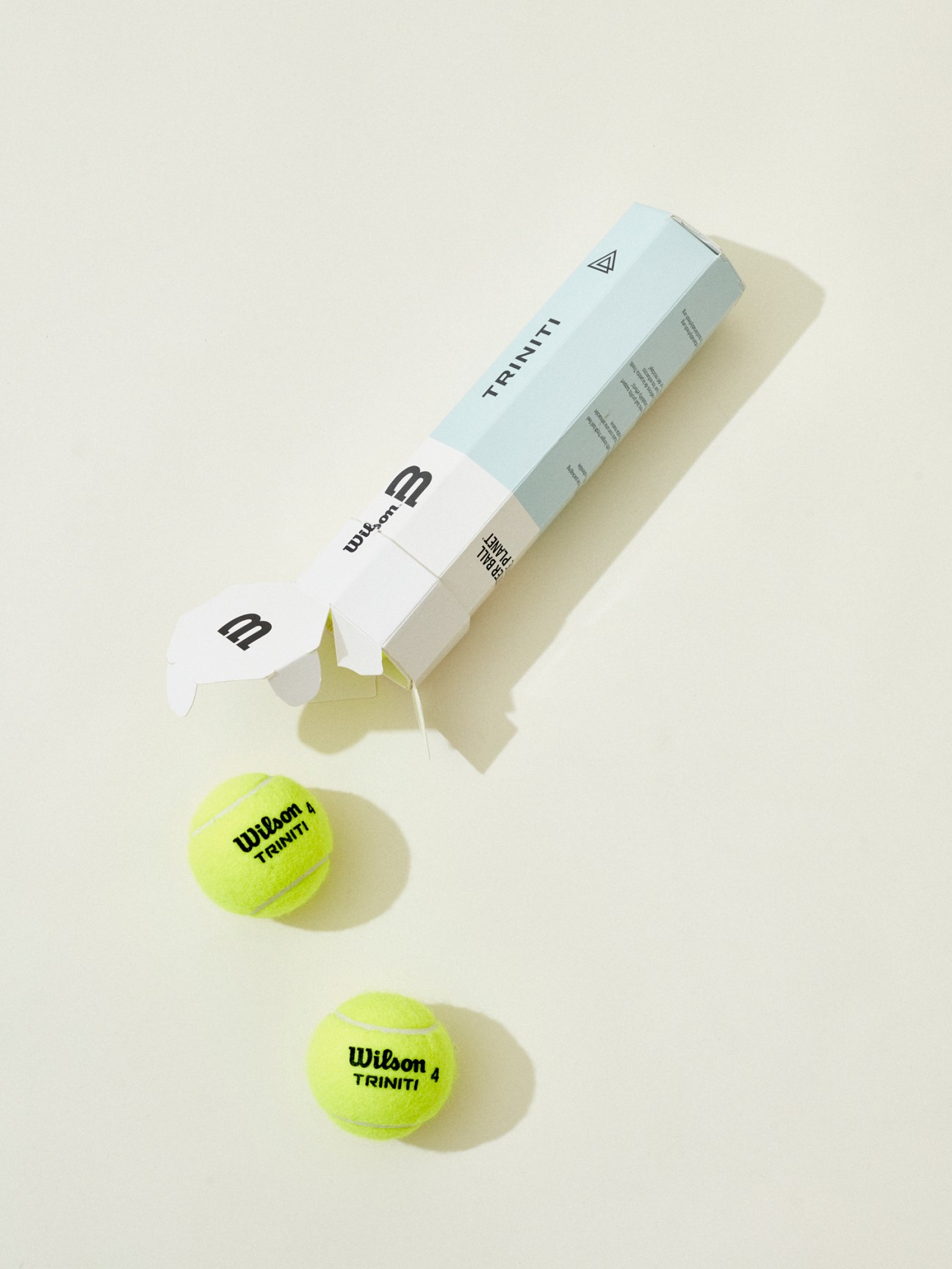 Two yellow Wilson tennis balls with tube of tennis balls on white background