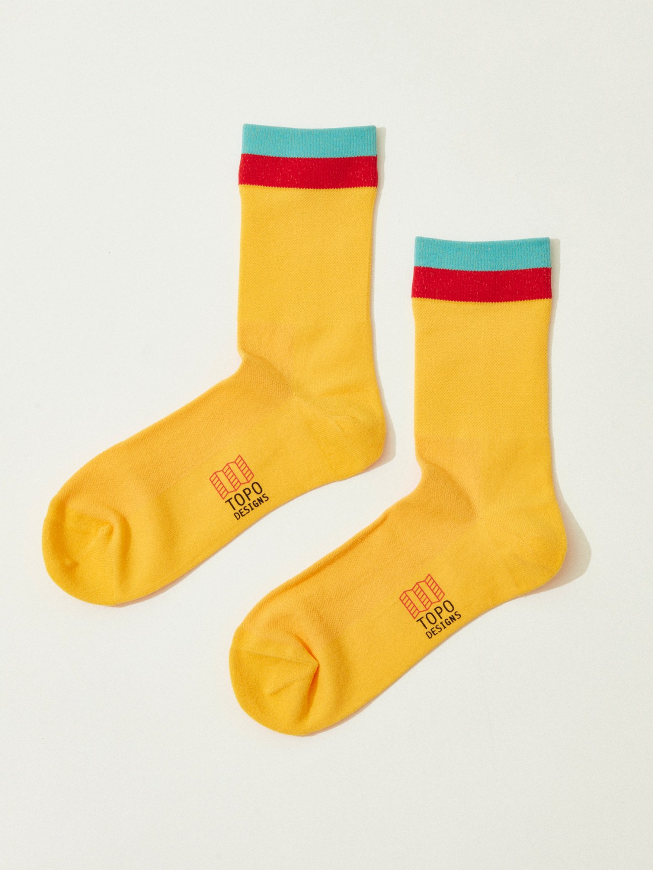 Pair of yellow wool socks with red and turquoise striped cuffs on white background