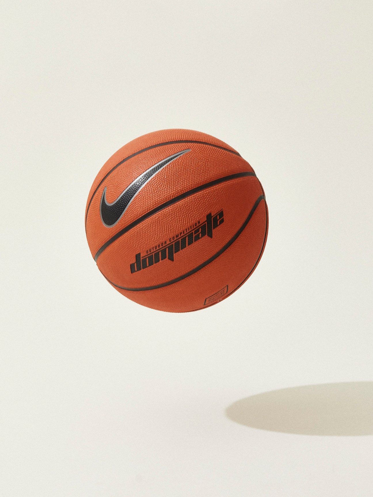Orange Nike basketball with black swoosh logo and Dominate text on white background