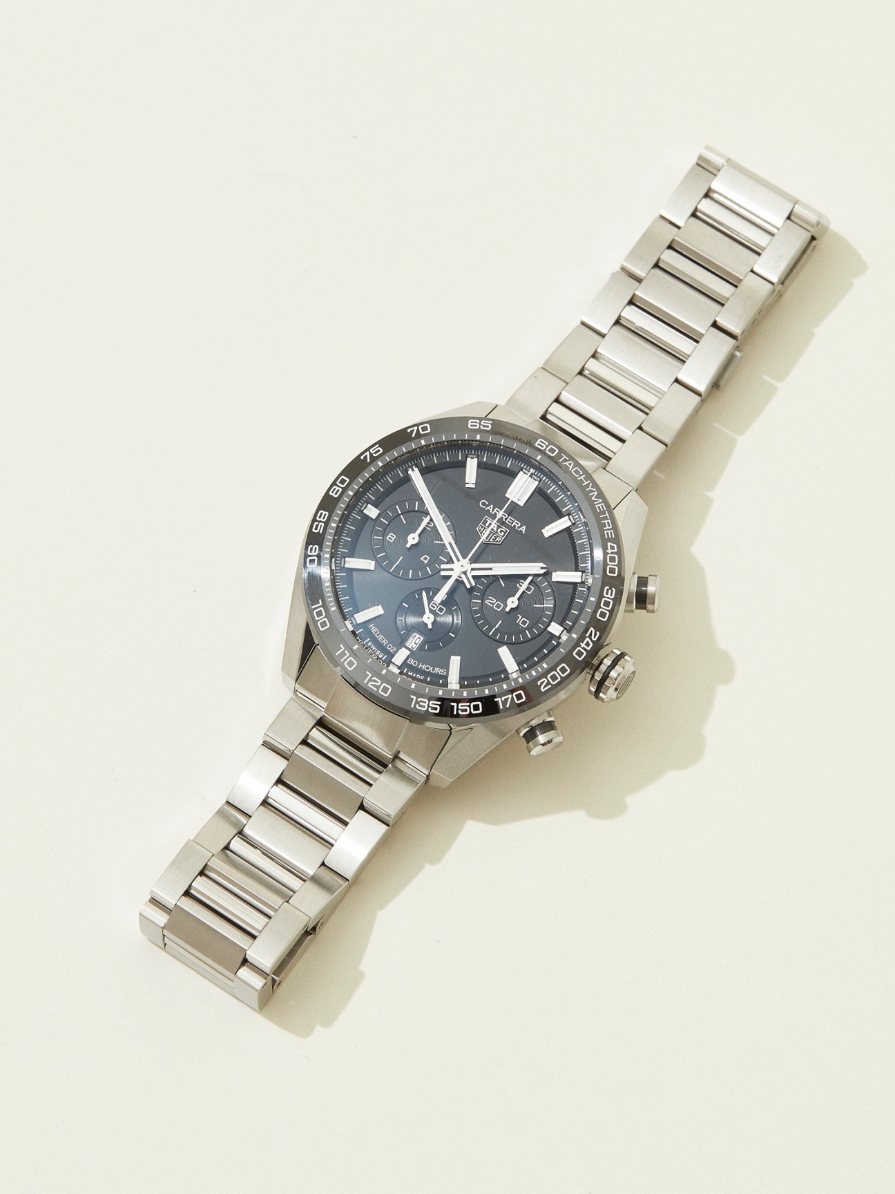 TAG Heuer sports chronograph watch with steel bracelet and dark dial on white background