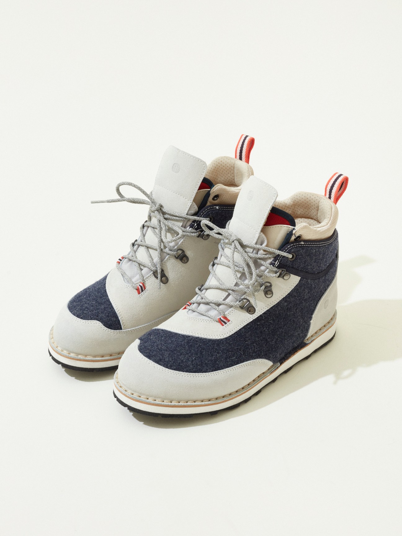 Pair of grey and navy hiking boots with white accents and laces on white background
