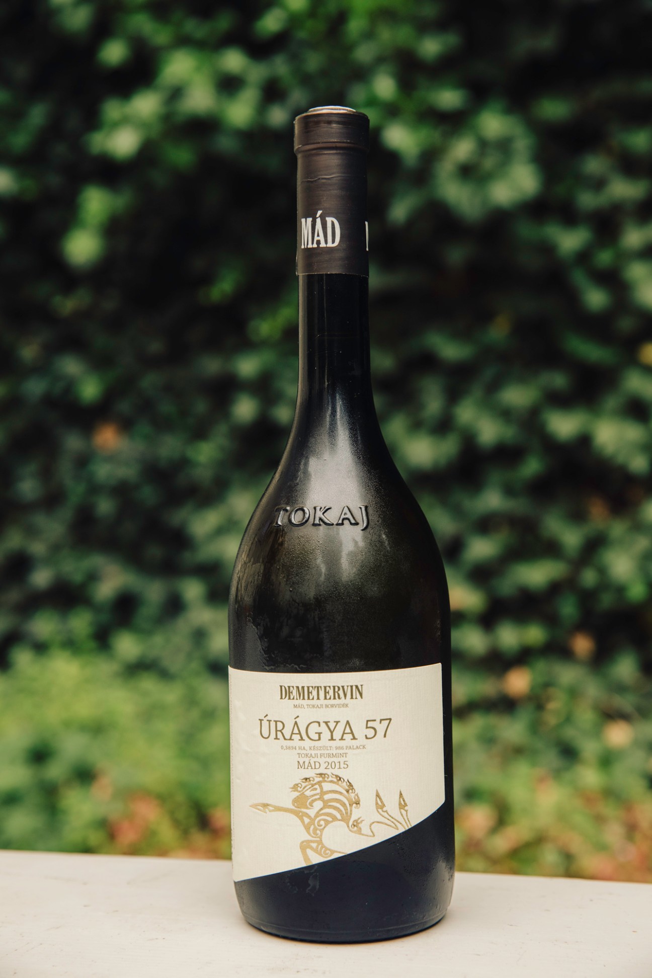 Demetervin Uragya 57 wine bottle from 2015 vintage displayed against blurred green foliage background