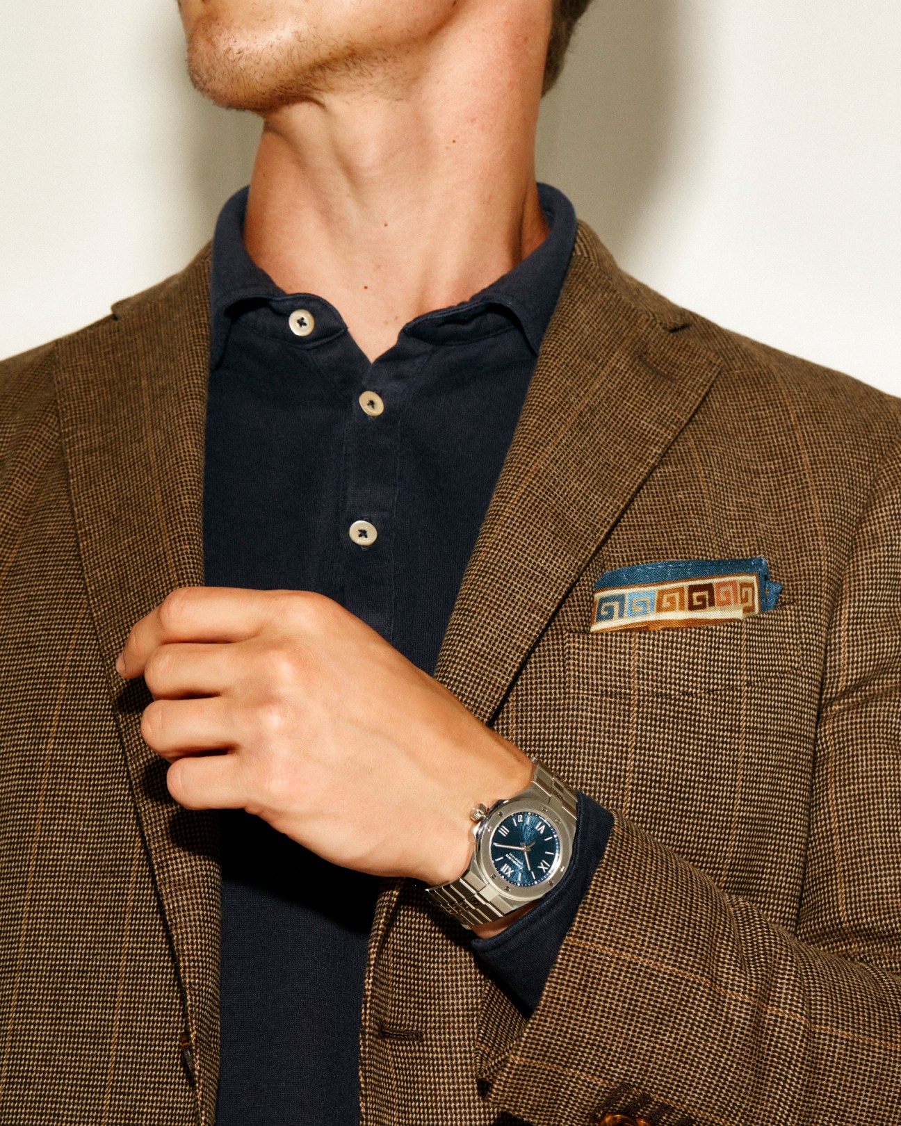 Man wearing Boglioli jacket and navy polo shirt with Drake's pocket square and Chopard Alpine Eagle watch.