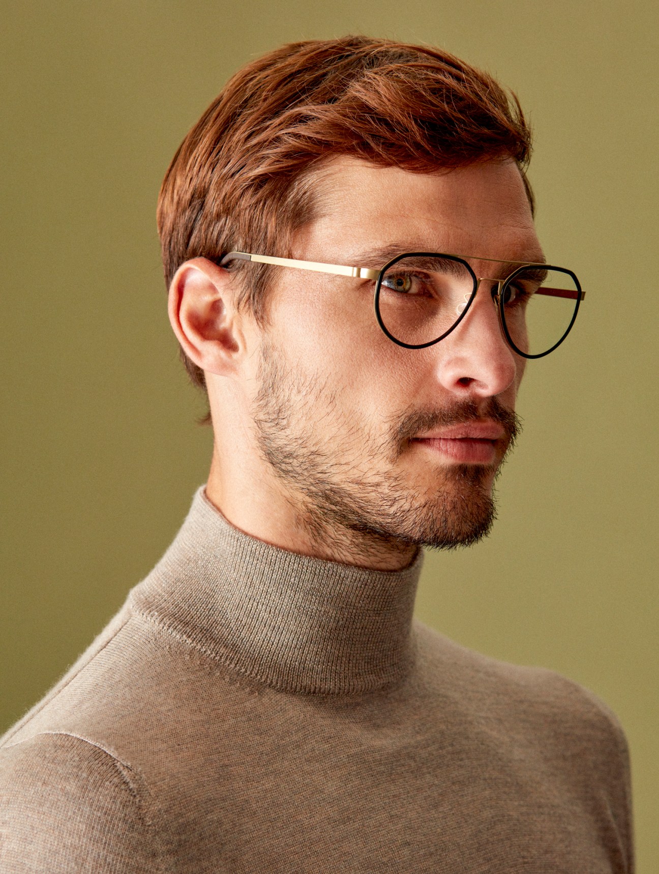 Model wearing light colored jumper and round-framed glasses