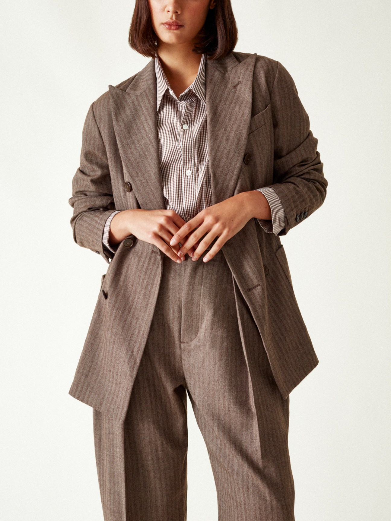 Woman wearing brown suit with matching blazer and trousers over checkered shirt