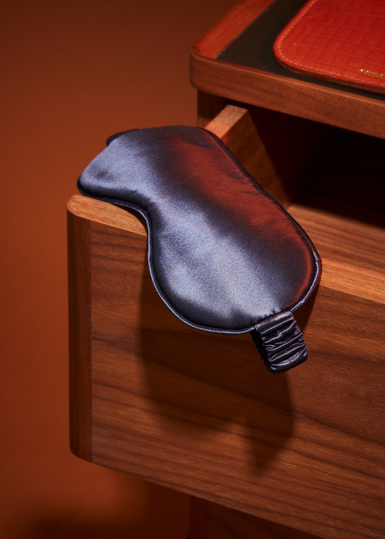 Dark leather sleep mask with elastic strap on wooden surface
