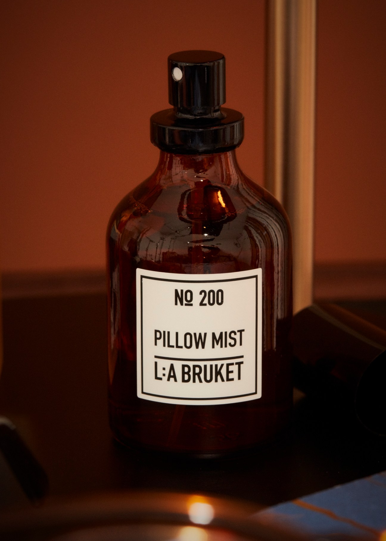 Brown glass bottle with black spray pump labeled 'No 200 Pillow Mist L:A Bruket'