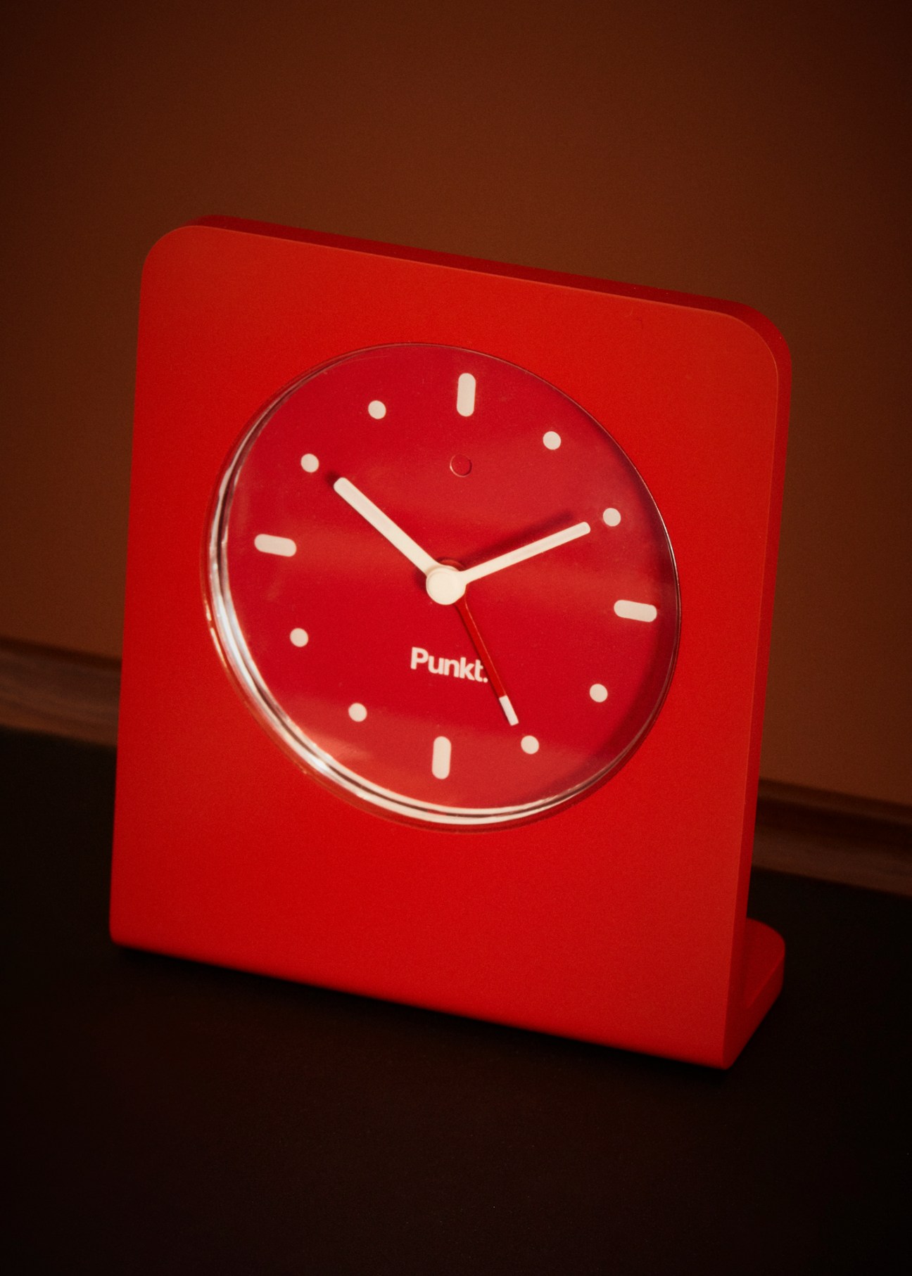 Red square alarm clock by Punkt with minimalist white hands and hour markers