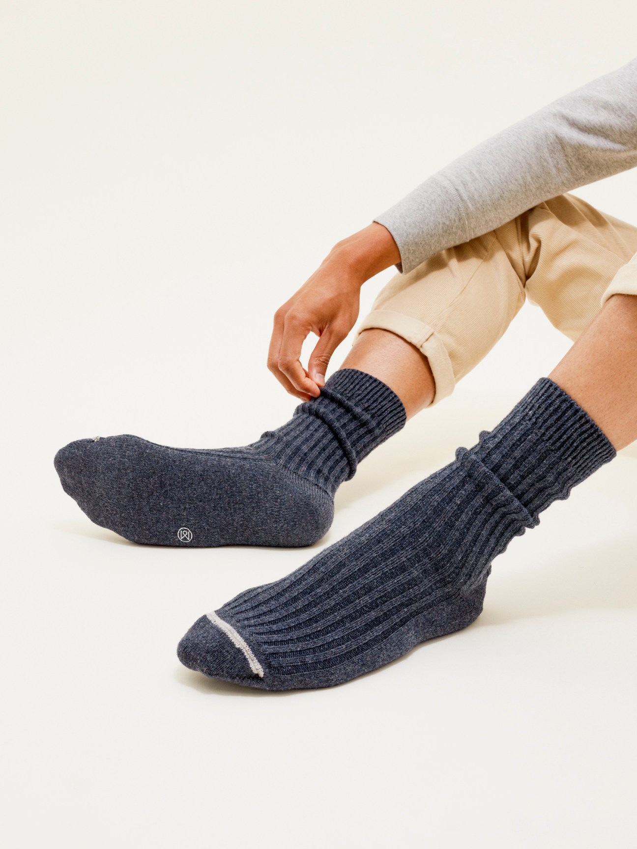 Person wearing navy ribbed wool socks by Monocle while adjusting them.