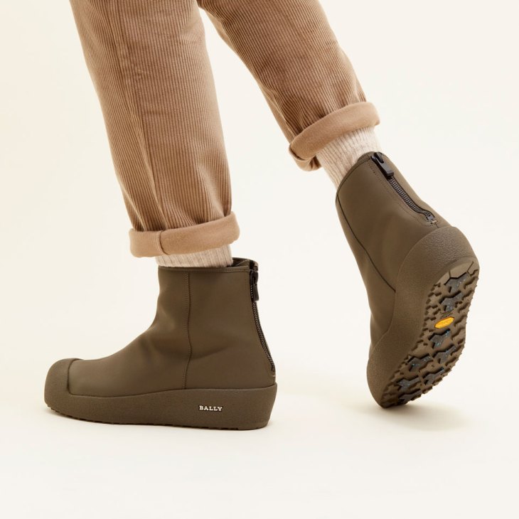 Person wearing olive green Bally x Monocle curling boots with corduroy pants and cream socks