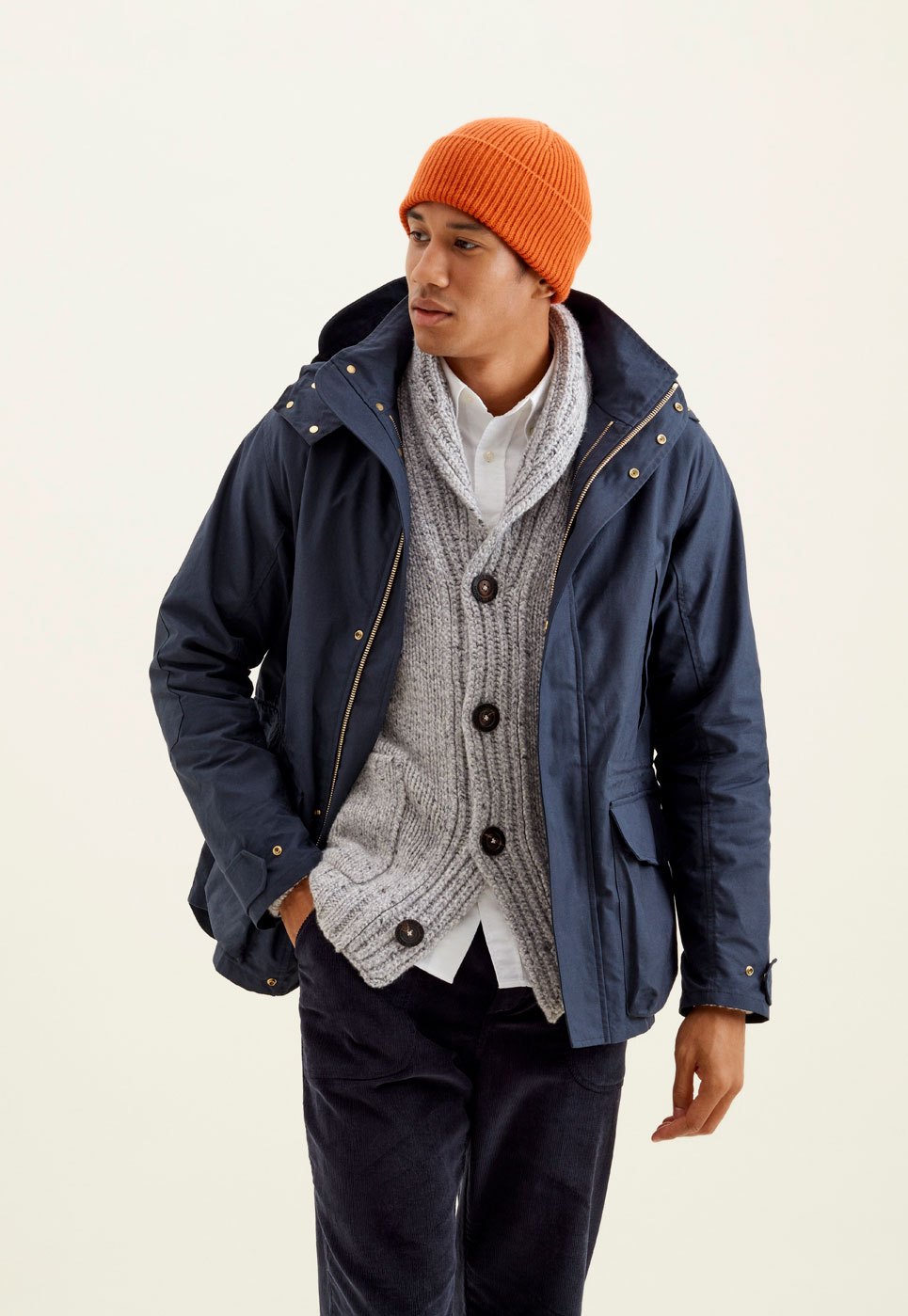 Man wearing orange beanie, navy jacket and grey cardigan in winter layered outfit