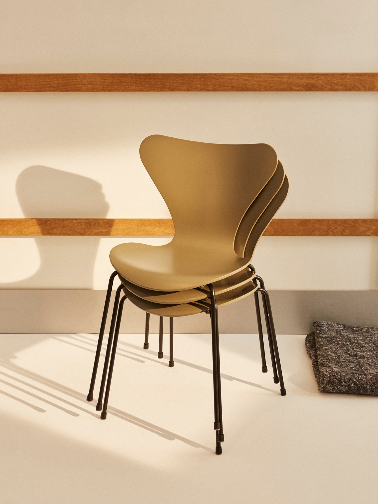 Three Fritz Hansen Series 7 chairs in warm yellow stacked together showing the molded plywood design