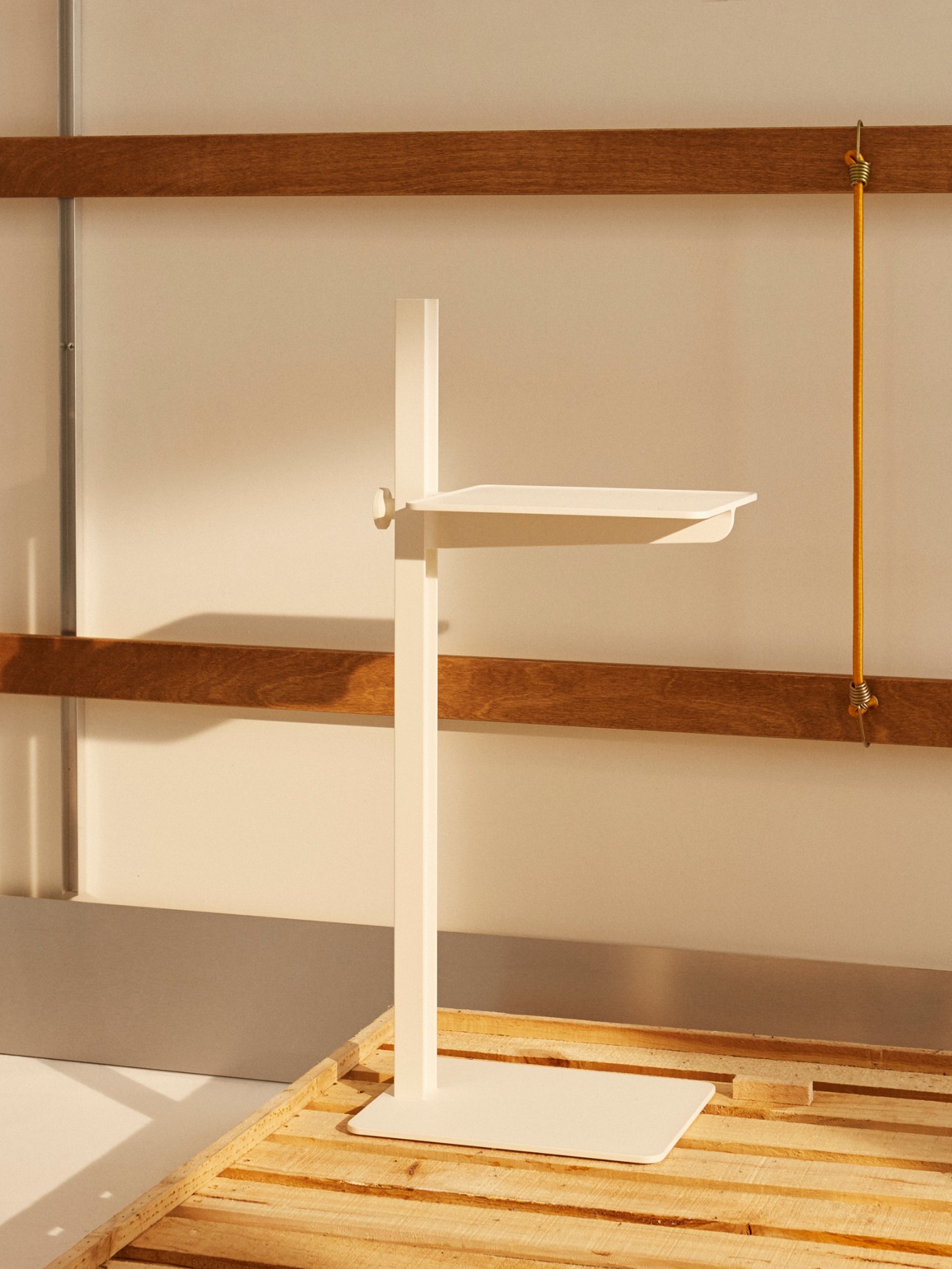 White adjustable side table with vertical post and horizontal platform on wooden floor