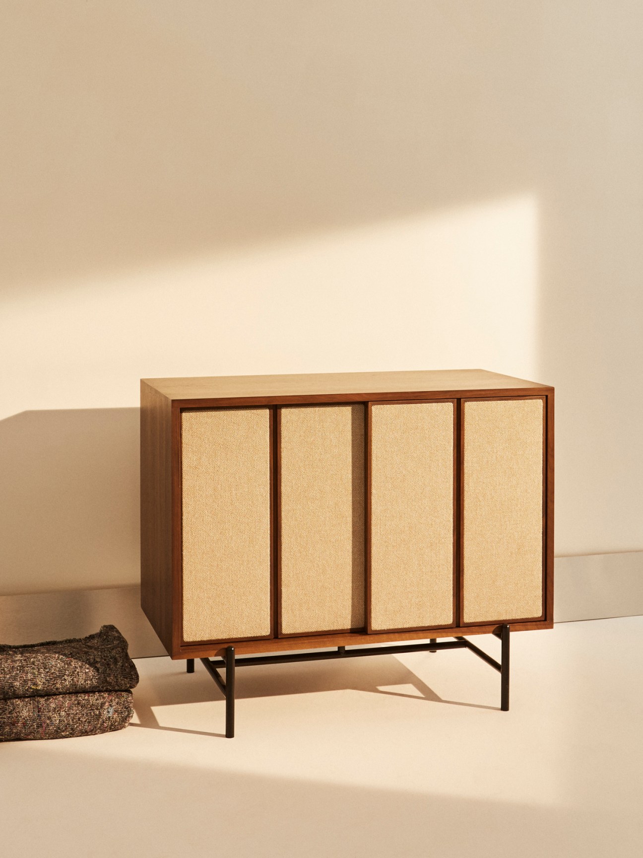 Canvas cabinet with ash and walnut frame and fabric-covered sliding doors showing modern British craftsmanship