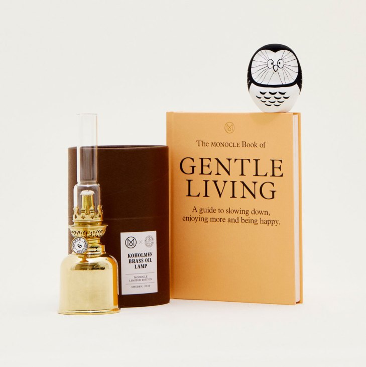 Curated gift collection featuring book, owl figure, brass oil lamp and other items on neutral background