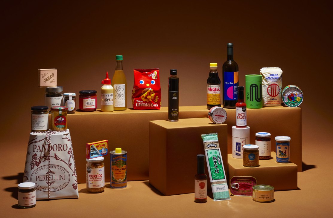 Artisanal food products arranged on stepped wooden platforms against warm brown background