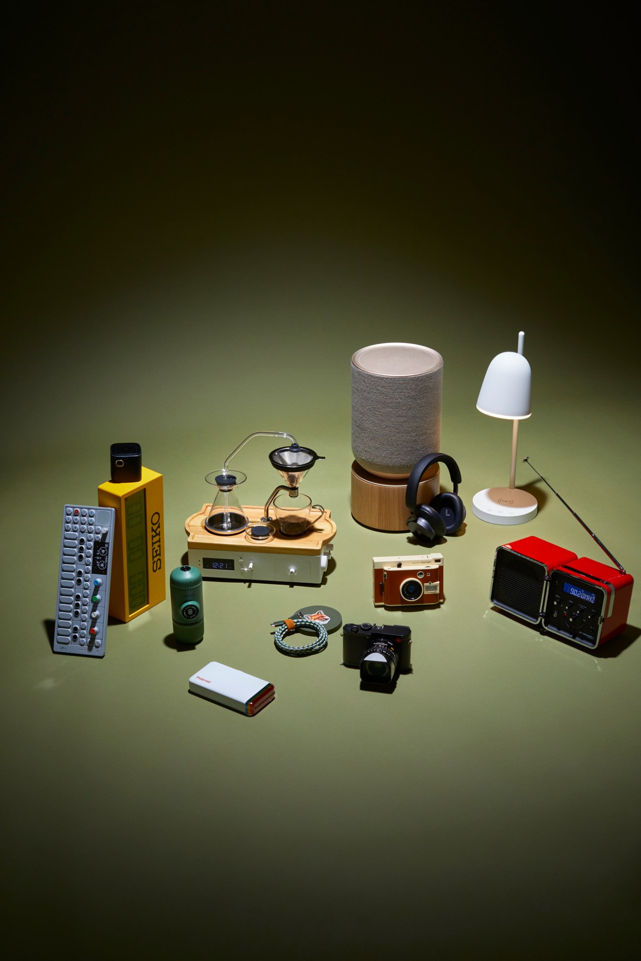 Various modern lifestyle products including cameras, speakers, headphones, and electronics arranged on neutral background