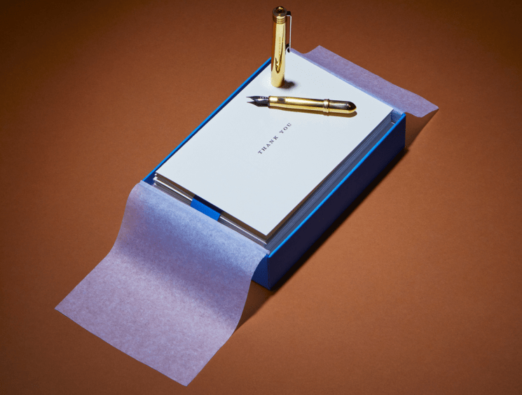 Notecard with a gold pen in an open gift box.