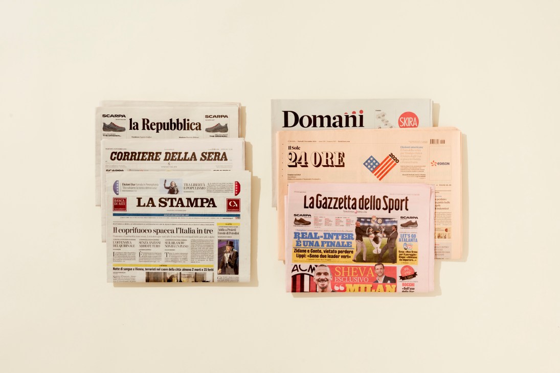 Italian newspapers and magazines arranged on a beige background, including La Repubblica, Corriere della Sera, La Stampa, Domani, Il Sole 24 Ore, and La Gazzetta dello Sport.
