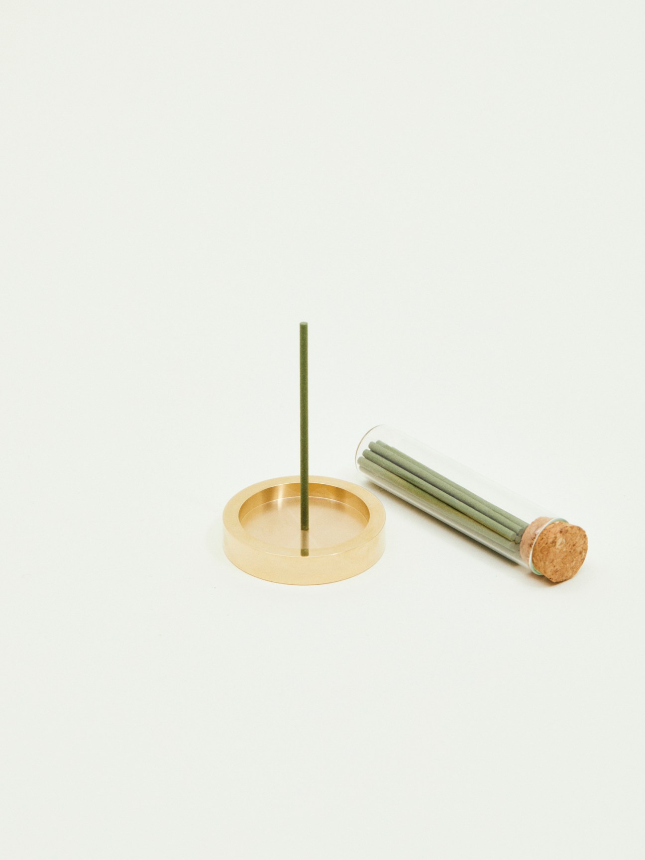Shoyeido Nanshu incense with brass holder and bundle of green incense sticks with cork base.