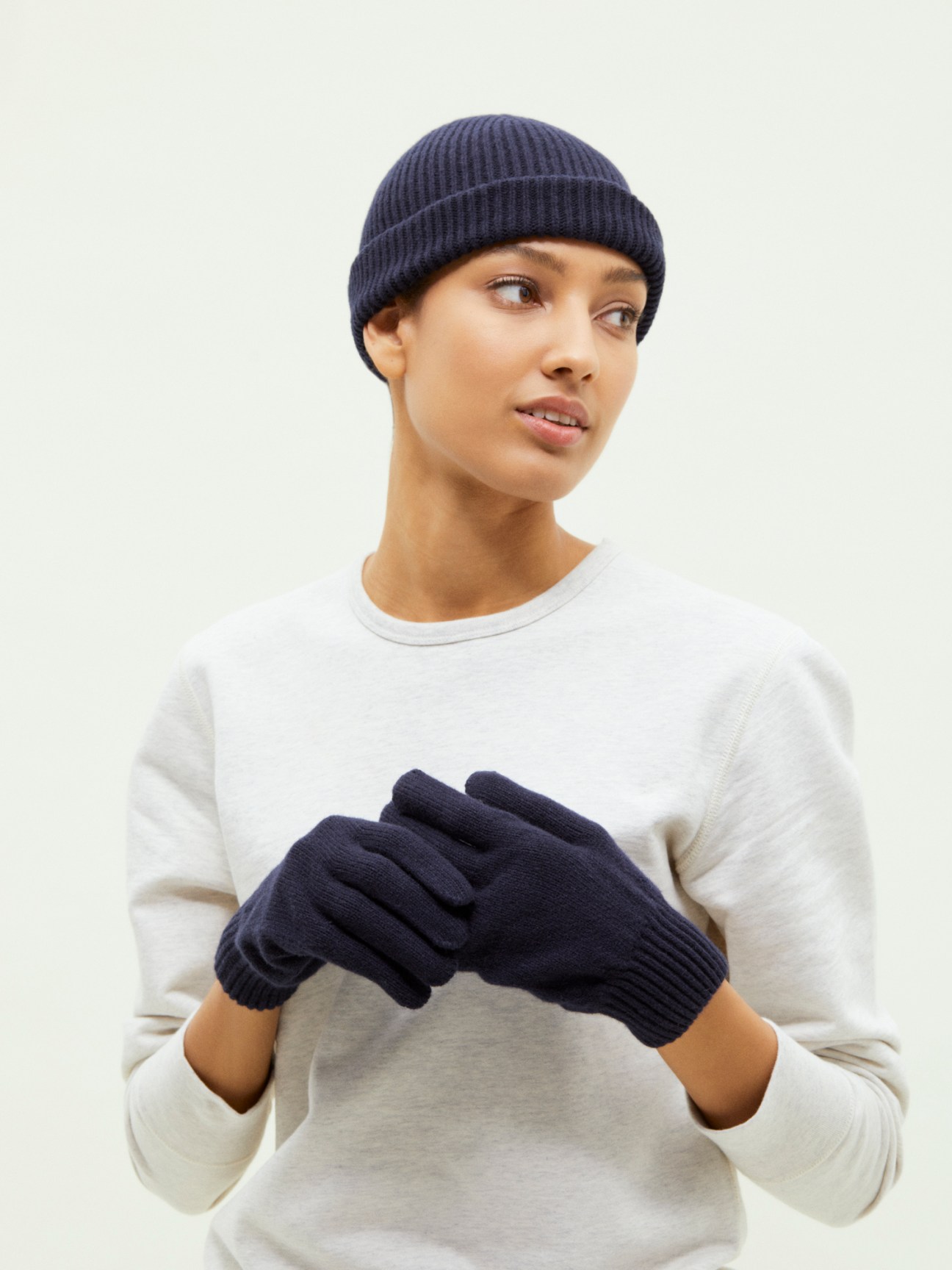 Model wearing Organic Basics navy recycled cashmere beanie and matching gloves