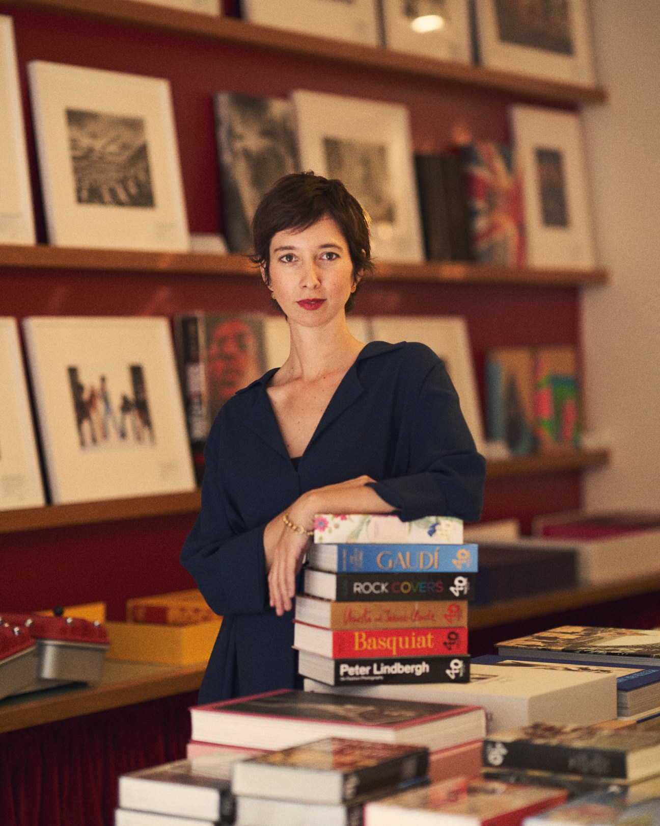 Marlene Taschen standing behind stacks of art books in Taschen's London Mayfair bookshop