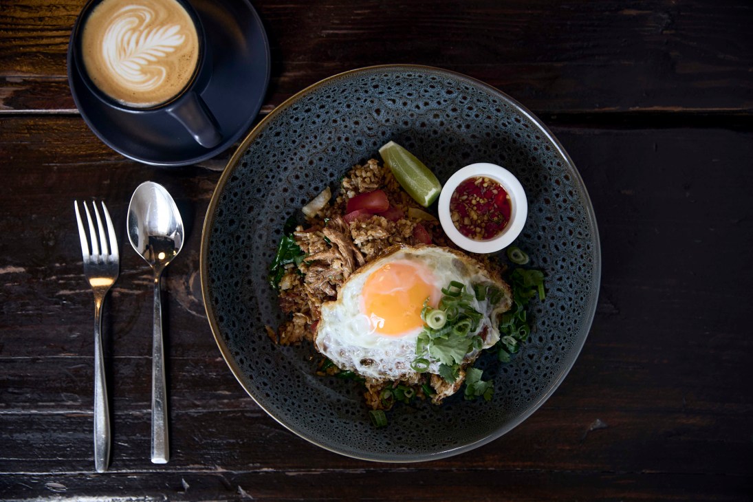 Thai-inspired breakfast dish with fried egg, vegetables and coffee with latte art at West End Coffee House
