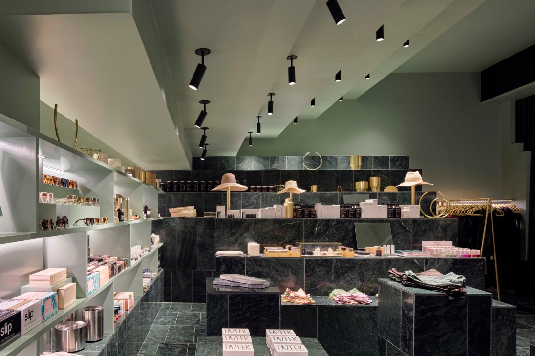 Interior of Museum of Small Things retail store with green marble displays, pink products, and pendant lighting