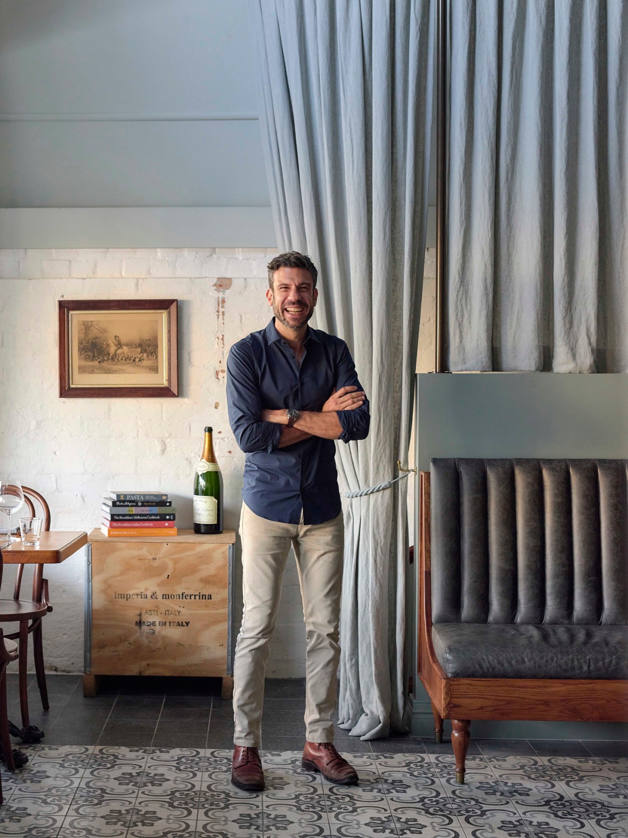 Mark Rotolone standing with arms crossed in casual attire in an elegant restaurant interior