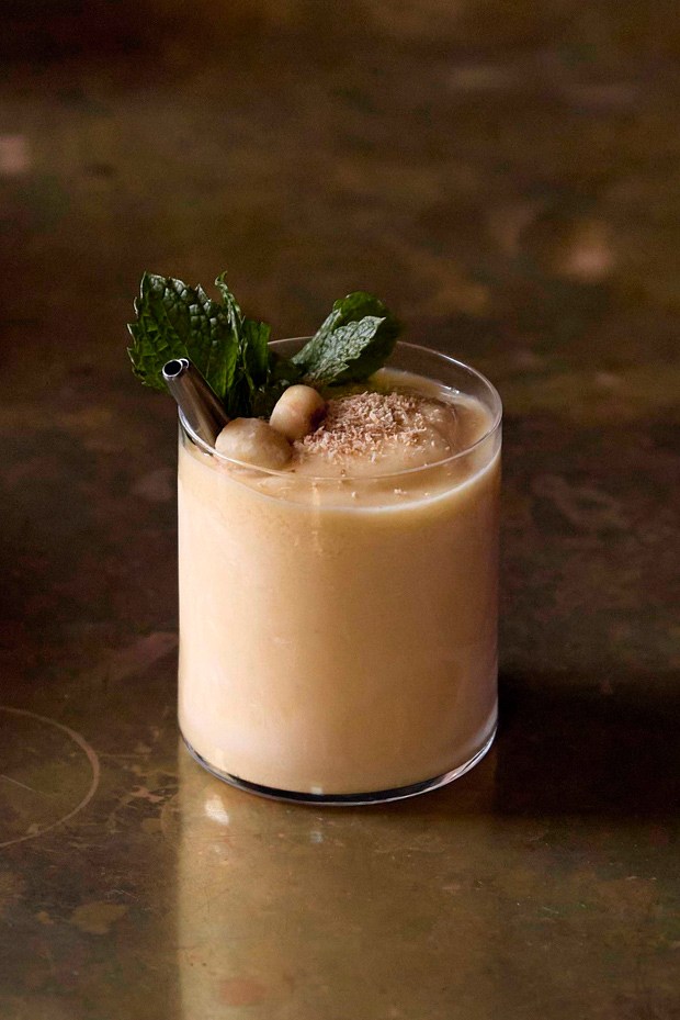 A creamy beige cocktail garnished with mint and what appears to be crushed ice or foam on top