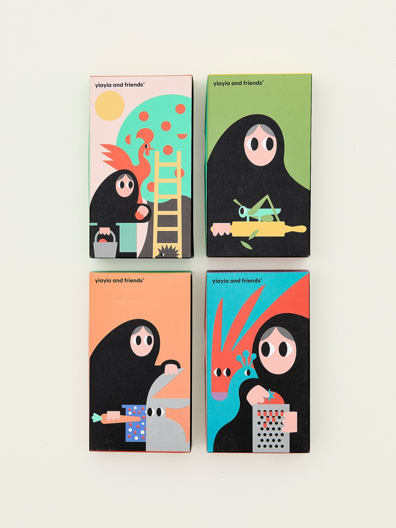 Four colorful illustrated product packages for Yiayia and Friends featuring a black-robed character with various food items