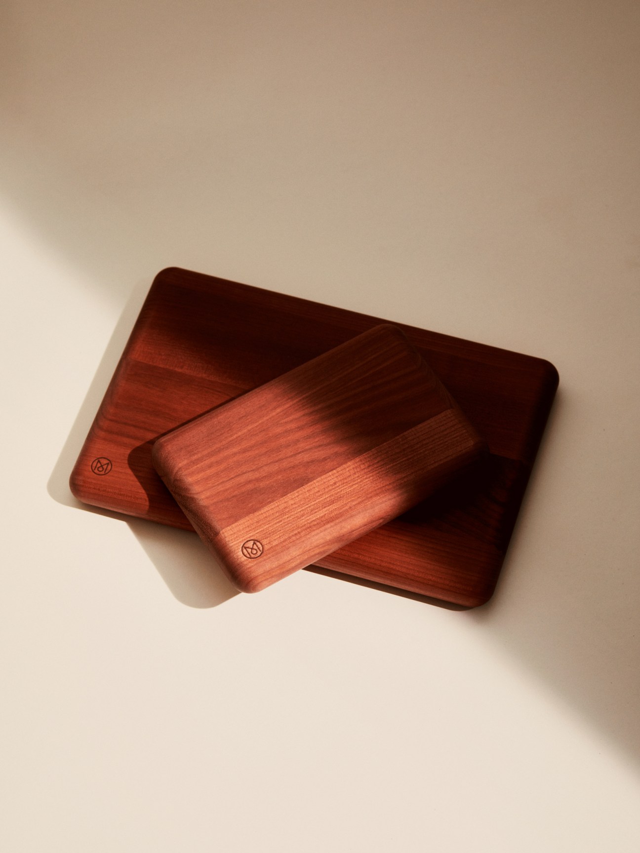 Two Swiss cherry wood cutting boards in large and small sizes stacked on white surface