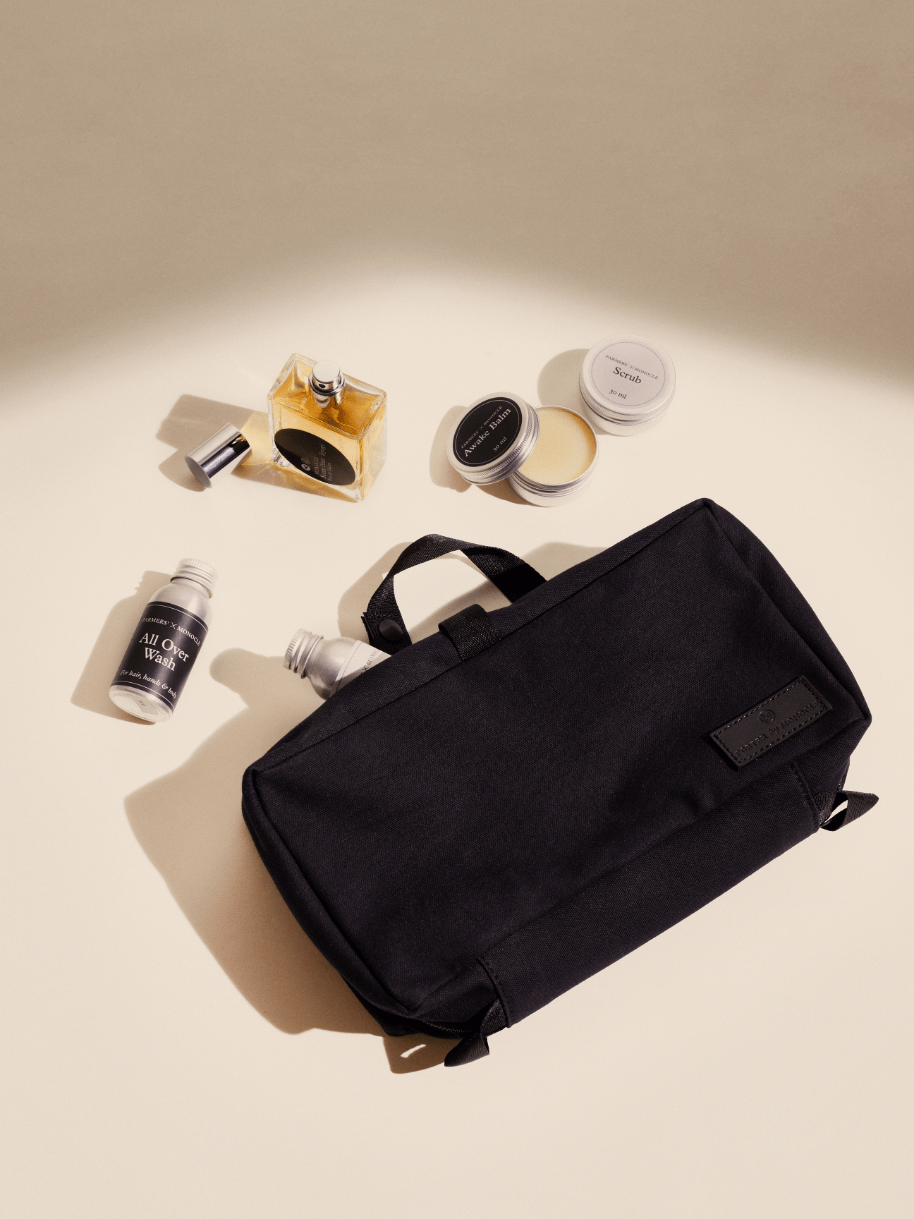 Black toiletry bag with various grooming products scattered around including perfume bottles and small containers