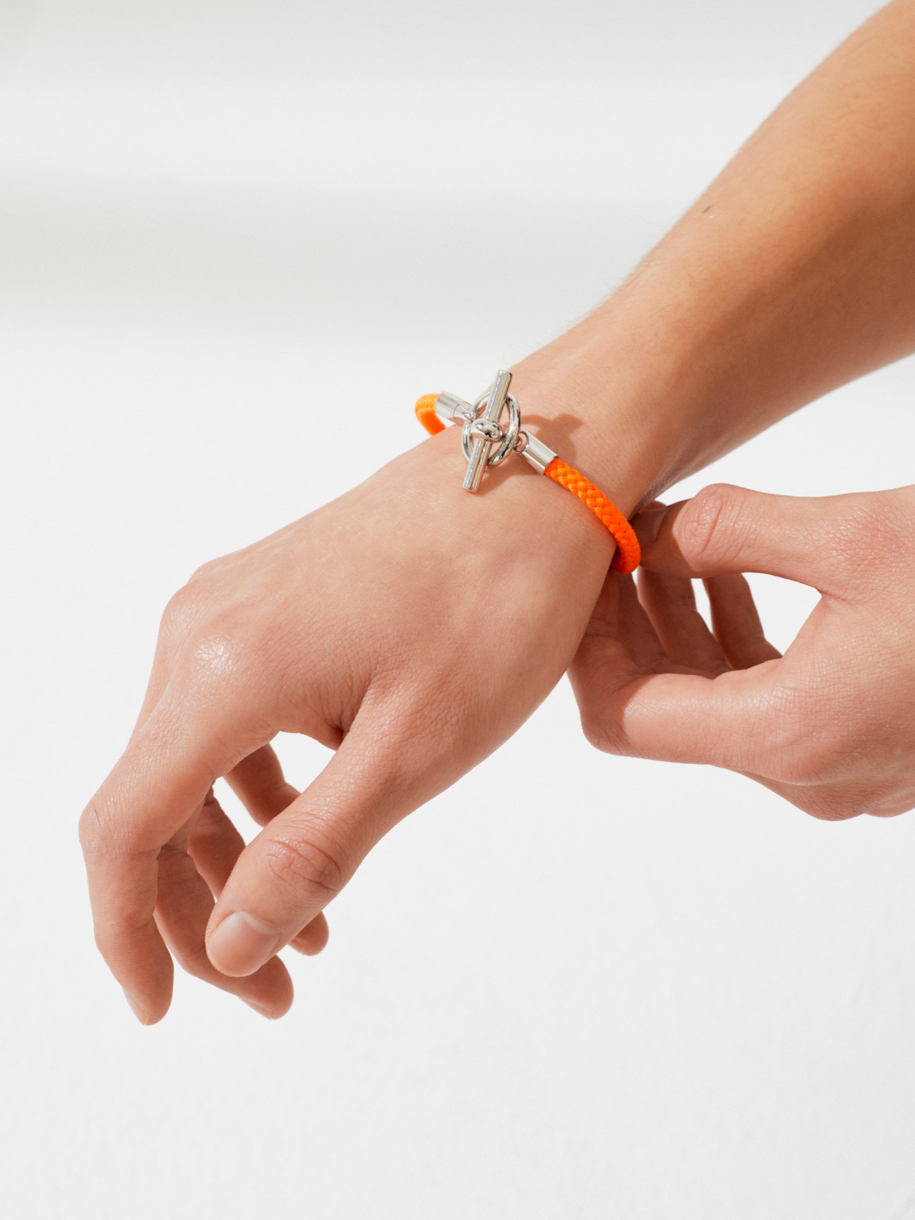 Orange braided bracelet with silver toggle clasp worn on wrist