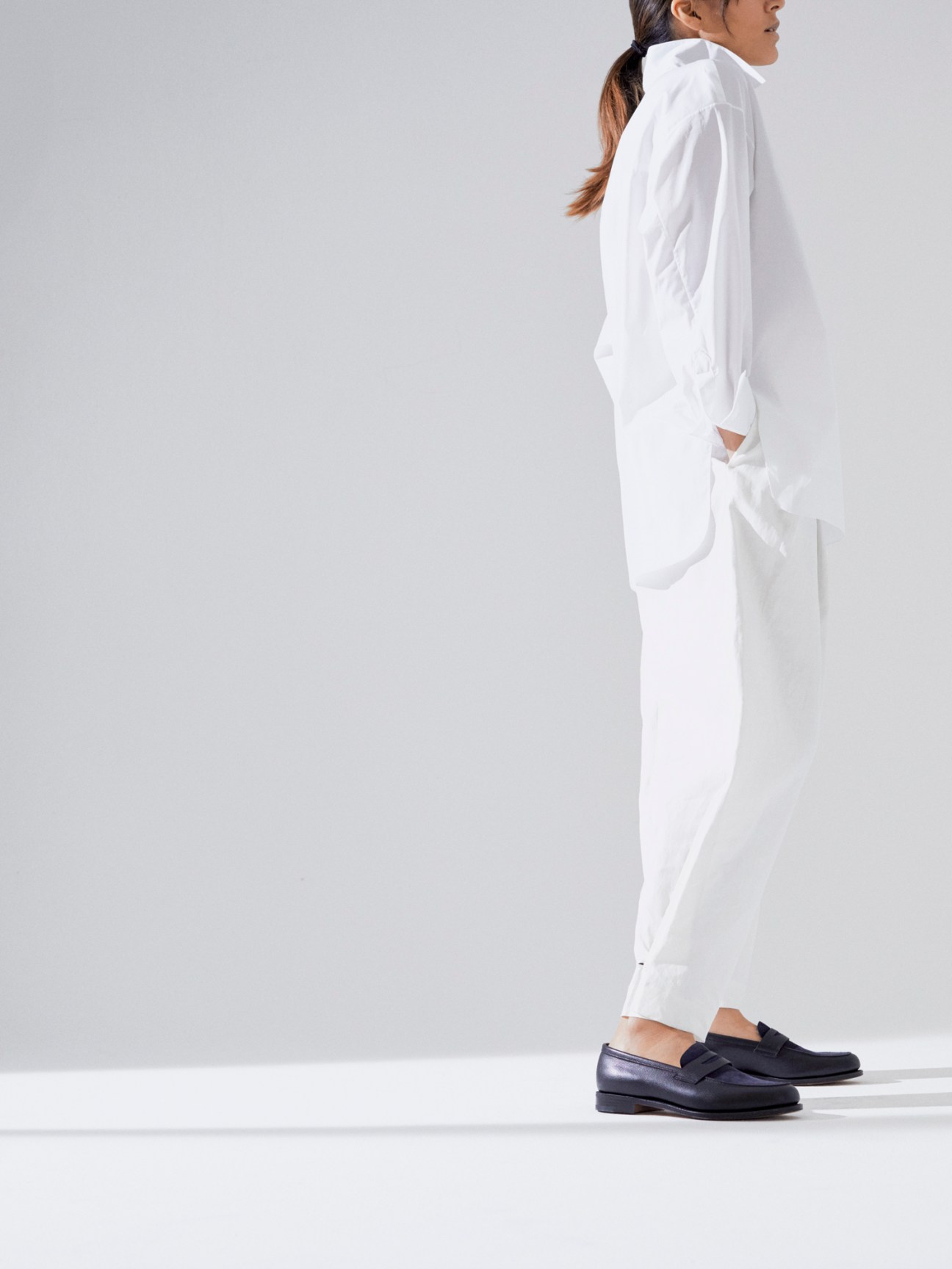 White button-down shirt, dark tailored trousers, and brown leather dress shoes in minimalist styling