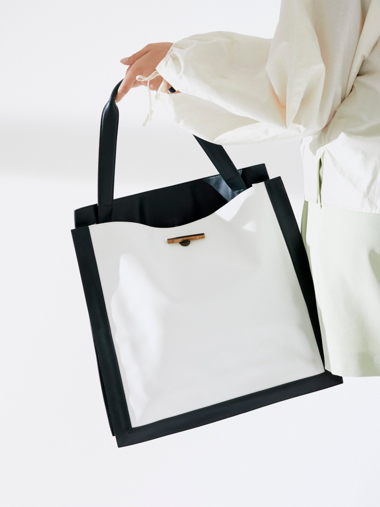 Two structured handbags by Sagan Vienna, one black and one light colored, photographed against white background
