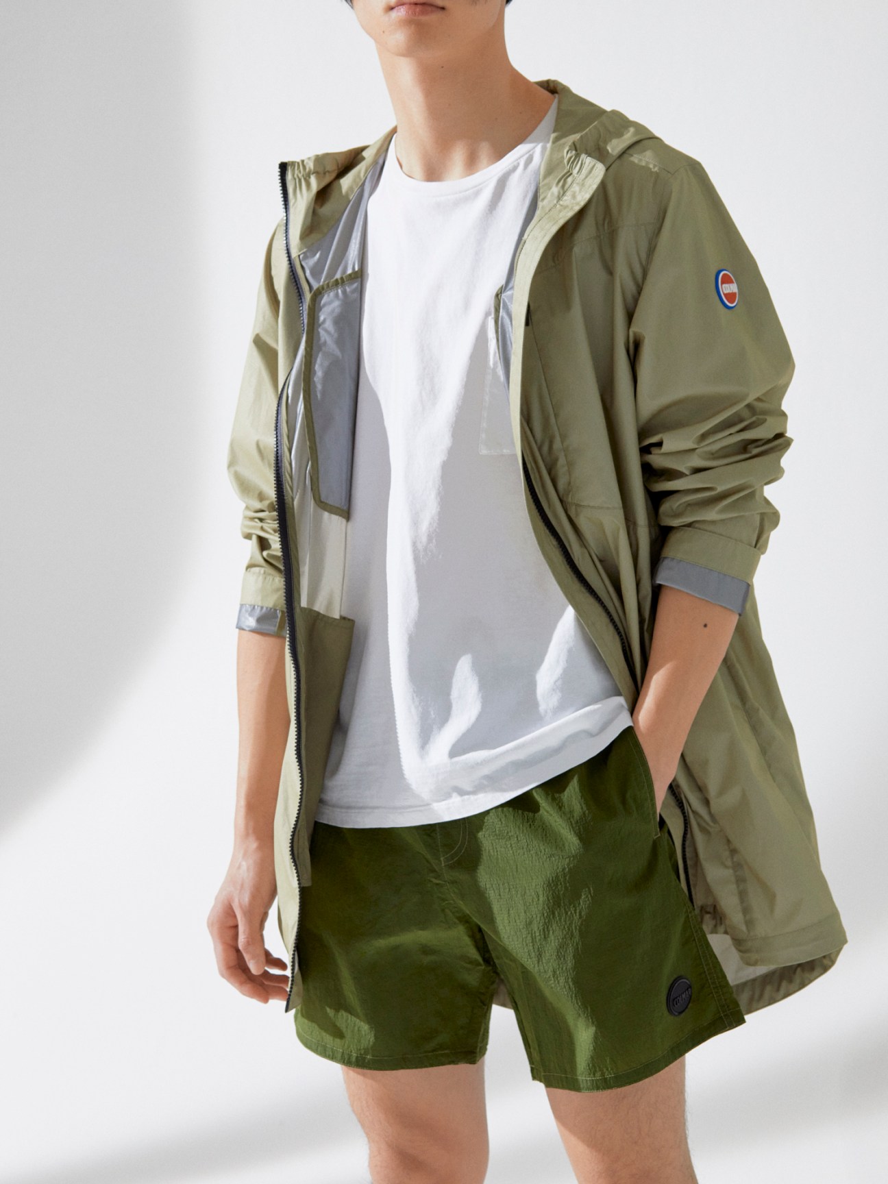 Man wearing olive green Colmar coat and swim shorts with white Barena Venezia t-shirt