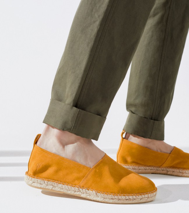Person wearing olive green trousers and orange suede espadrilles with rope soles