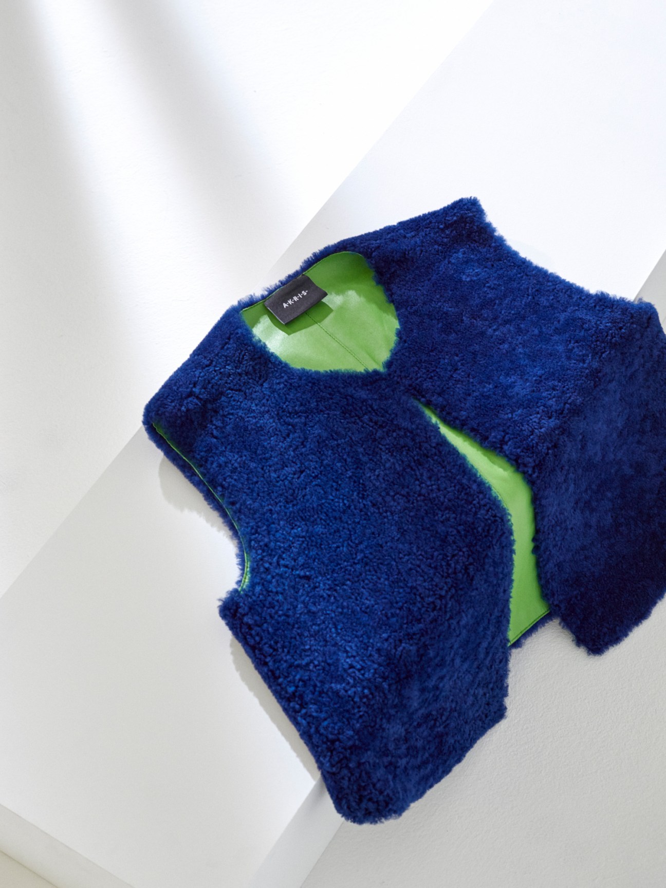 Blue fuzzy textured vest by Akris displayed against white background