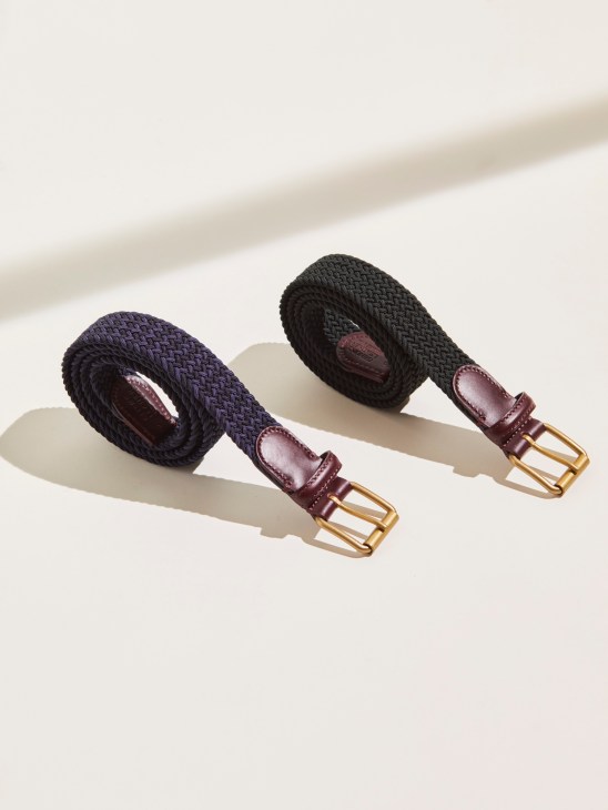 Two narrow elastic belts with woven dark fabric and burgundy leather details with brass buckles.