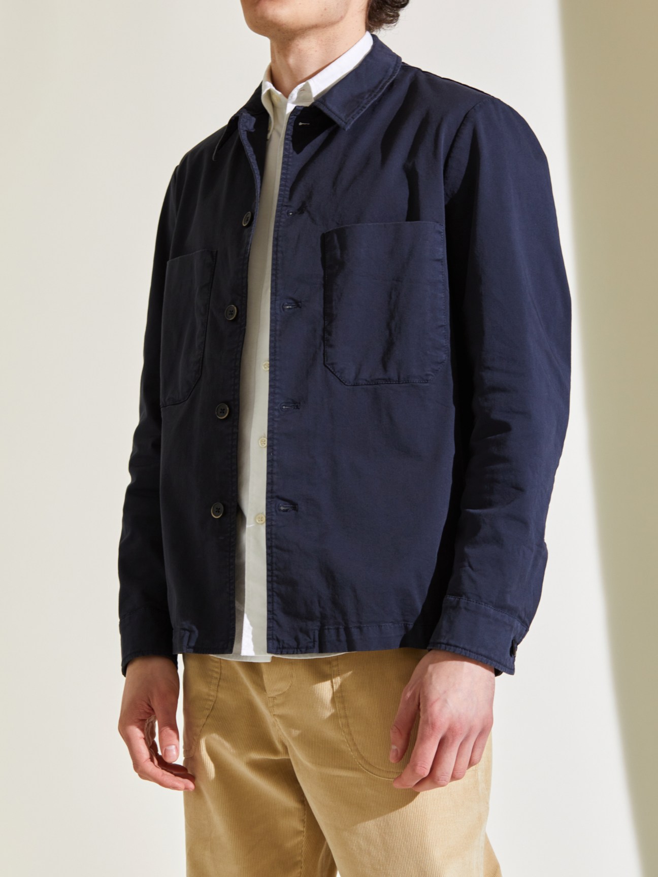 Person wearing navy Barena cotton overshirt with button front and chest pocket over white shirt and tan pants