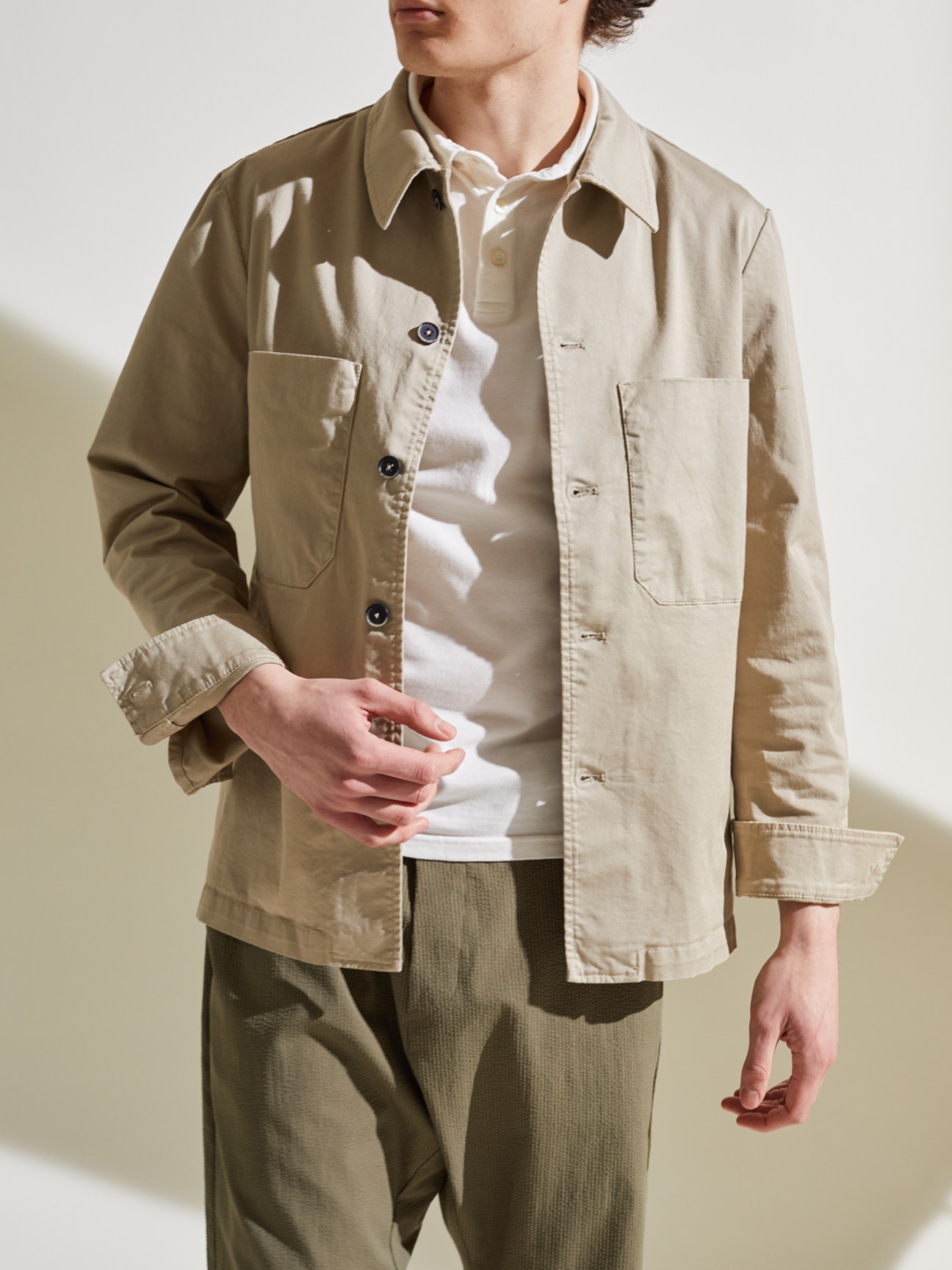 Person wearing stone colored Barena x Monocle cotton overshirt with patch pockets and neat collar