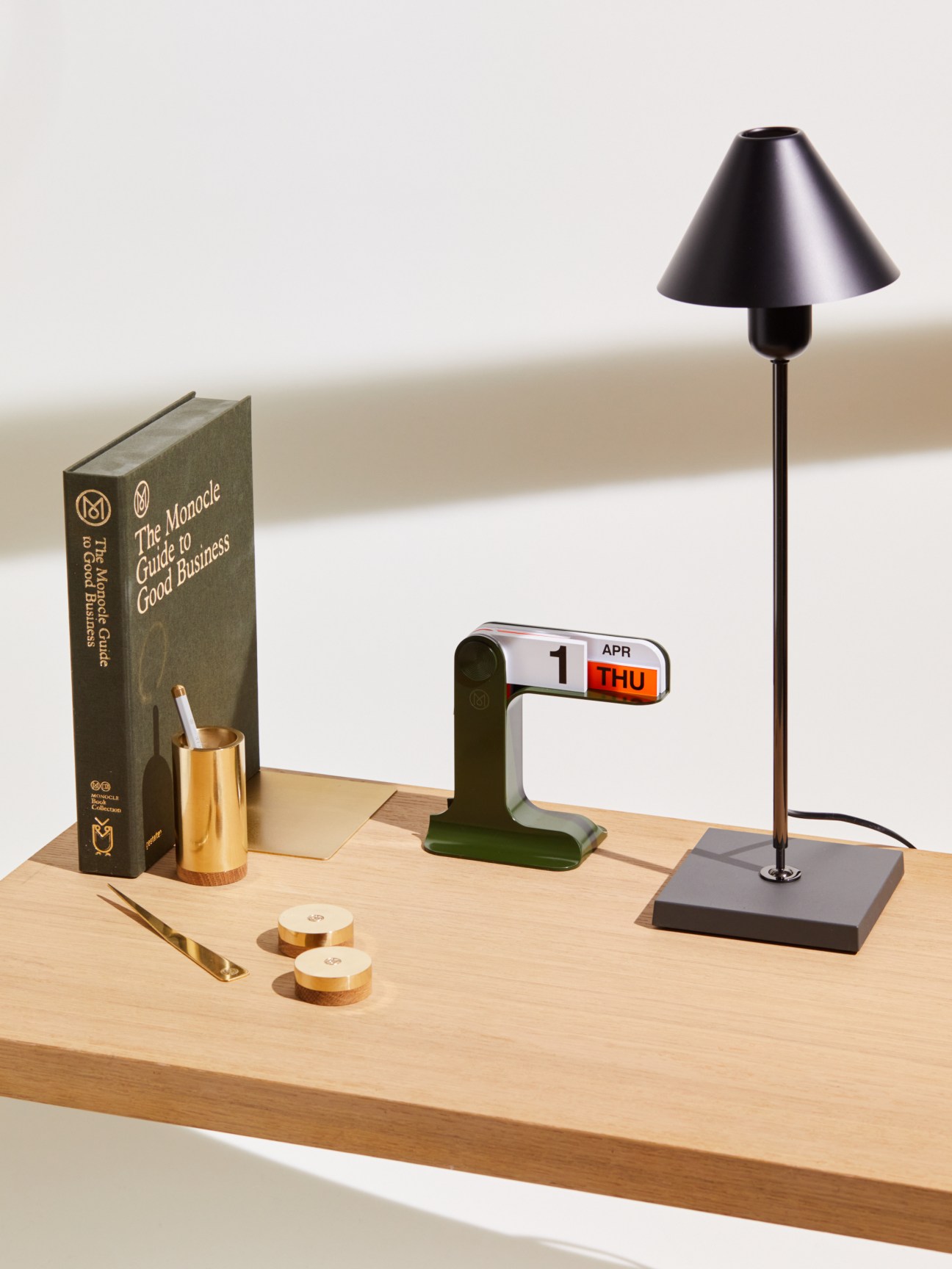 Styled desk setup with Danese Milano Timor perpetual calendar, brass pen holder, lamp and Monocle book